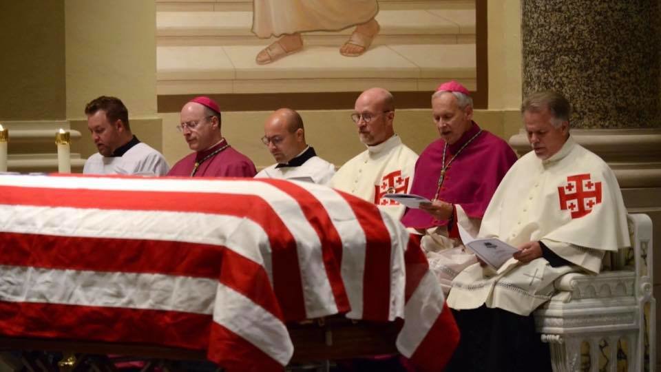 Bishop W. Shawn McKnight, second from left, prays the Office of the Dead with the priests of the Diocese of Wichita. Before them is the flag-draped coffin of Servant of God Father Emil Kapaun on Sept. 28 in the Cathedral of the Immaculate Conception.